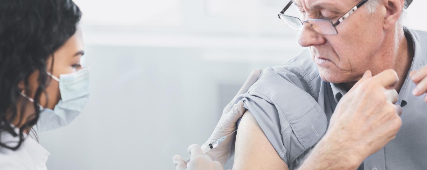 Pharmacist administering shot to elderly patient